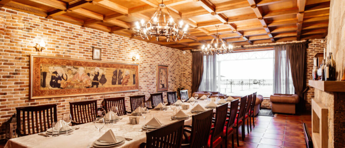 restaurant table for 14 persons at restaurant hall with brick walls wide windows and wood ceiling